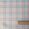 A close-up of the Multi Gingham 100% Linen Fabric showcasing its fine, yarn-dyed plaid pattern in blues, peaches, and creamy oatmeal