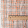 Earthy plaid linen fabric with vivid pumpkin threads and natural texture, suitable for creating comfortable and stylish wardrobe staples.