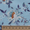 Blue Floral Linen Fabric, lightweight 135 GSM, with delicate white and orange flowers and blue and purple foliage on a soft blue background, ideal for summer dresses and home decor