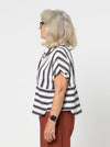 Lady wearing a black and white striped shirt made with the Blaire Shirt Sewing Pattern – Square-shaped with rolled cuffs and overlay.