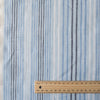 Vintage-style Blue Multi Stripe 100% Linen Fabric with varying stripes in navy, blue, and white on a light blue background, offering a washed-out look.