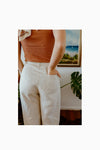 Lady wearing natural colour linen pants made of Bottlebrush Pants and Shorts Sewing Pattern - High-Waisted Flared Pants and Mini Shorts