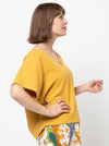 Joan Woven Top sewing pattern featuring a square shape, V-neck, extended shoulder line with band, and wide hem facings, suitable for washed linen, charmeuse, crepe, and rayon fabrics.